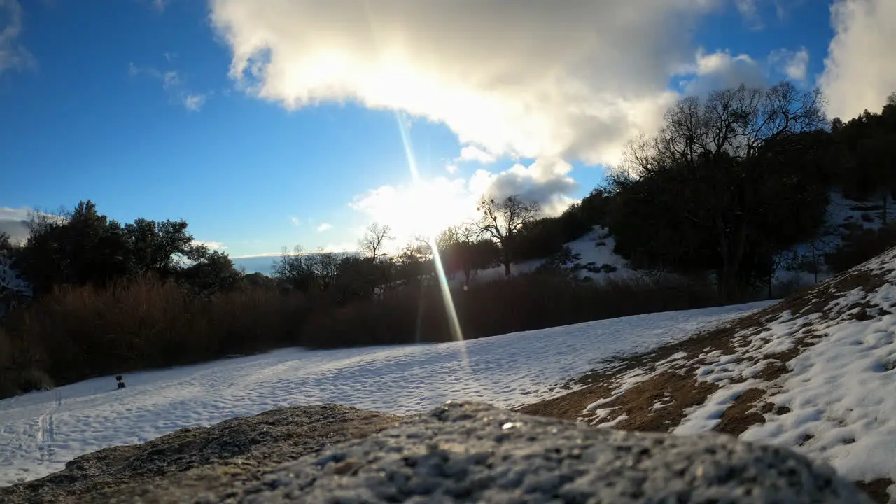 Clouds blow over the snowy mountain peak as shadows move across the landscape time lapse