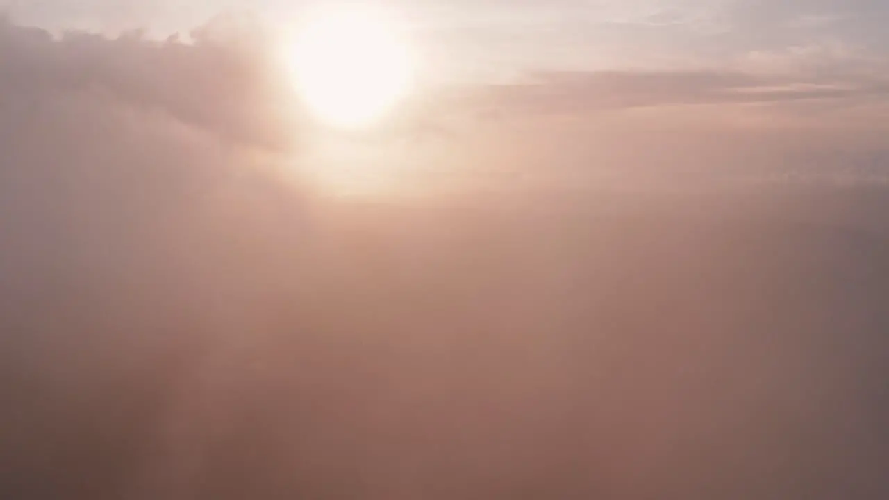 Incredible aerial view flying through light heaped up and wispy clouds in golden sunset sunrise