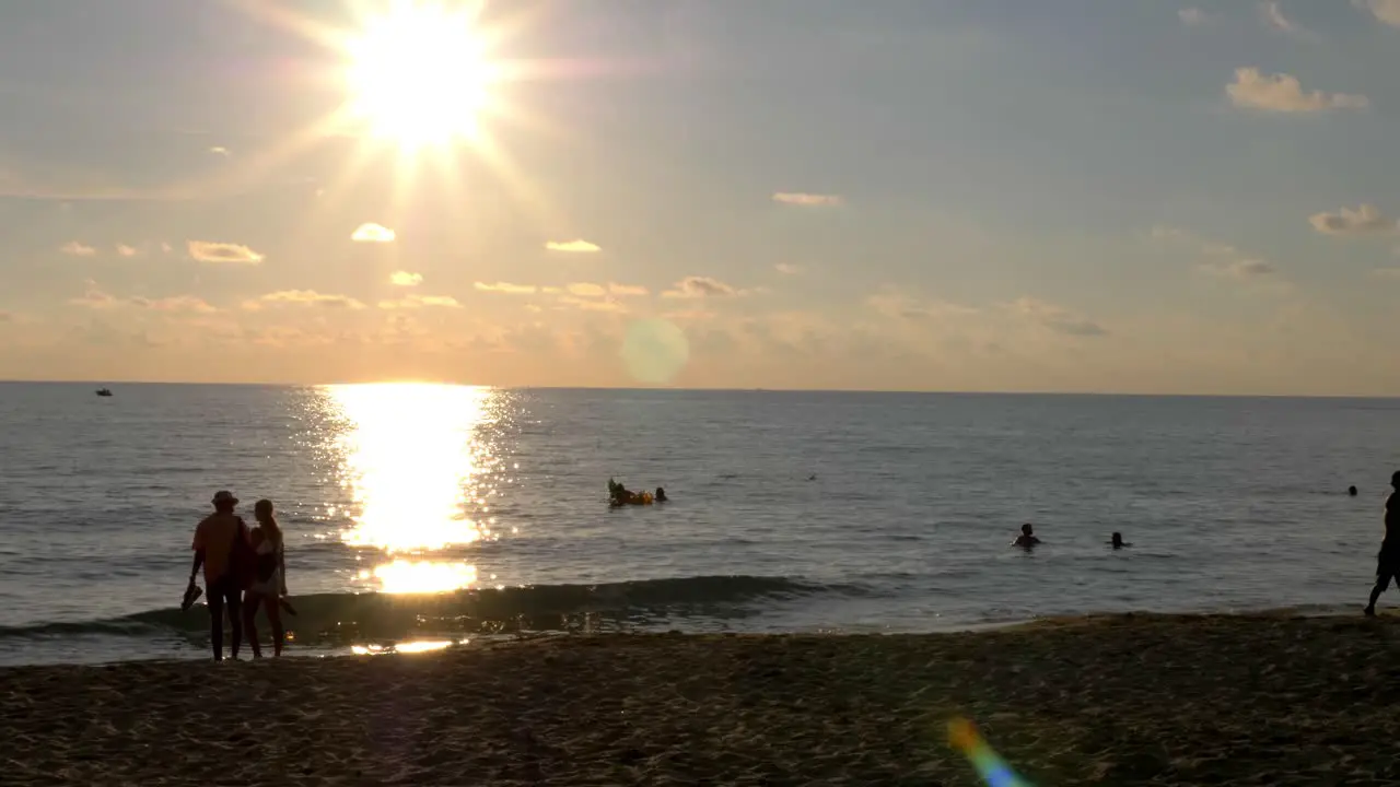 Tourists walking on the beach at sunset people playing frisbee