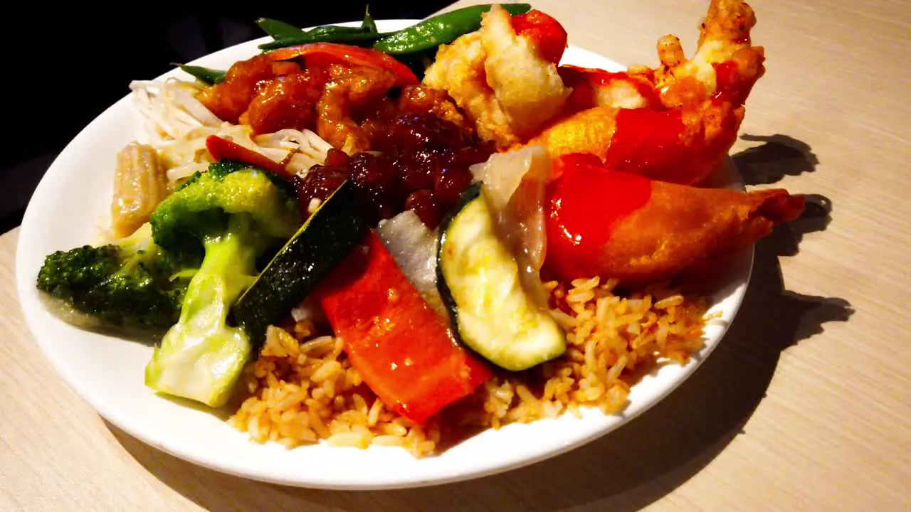 Chinese Food Plate Piled with popular favorites of deep fried breaded chicken balls n prawn shrimps with baby corn bean sprouts soy beans sliced zucchini fried rice sliced peppers rotating plate table