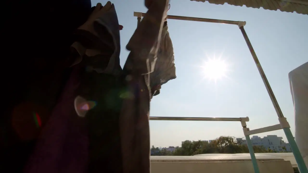 As the sun shines on an urban high rise apartment balcony a person hangs laundry to dry