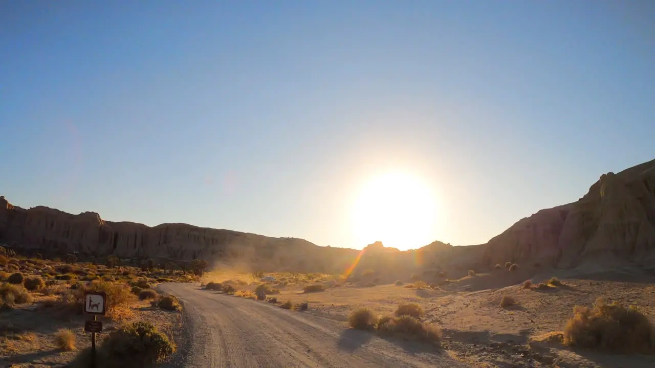 Driving along a dirt road in the famous RedRock Canyon State Park as the sun sets behind the sandstone cliffs