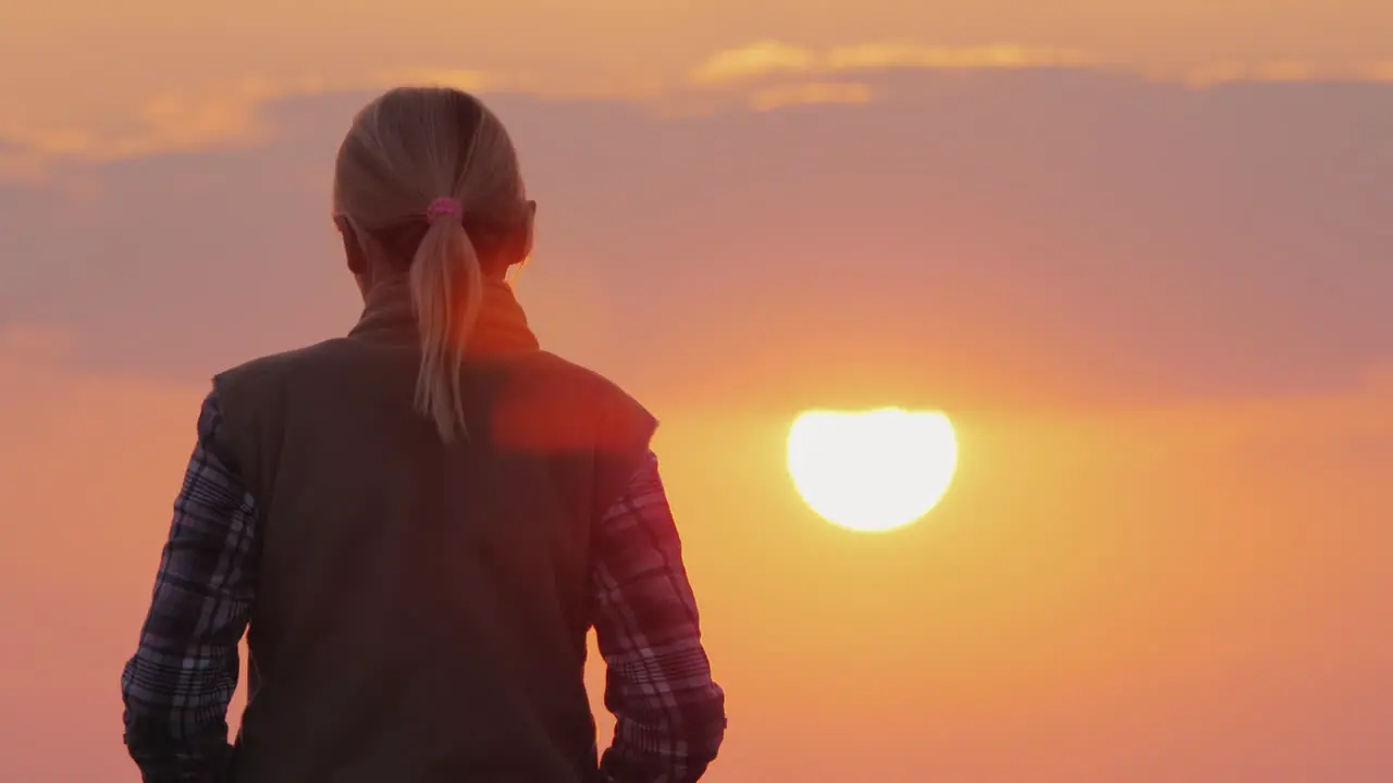 A Silhouette Of A Woman Walking Forward Towards The Big Red Sun