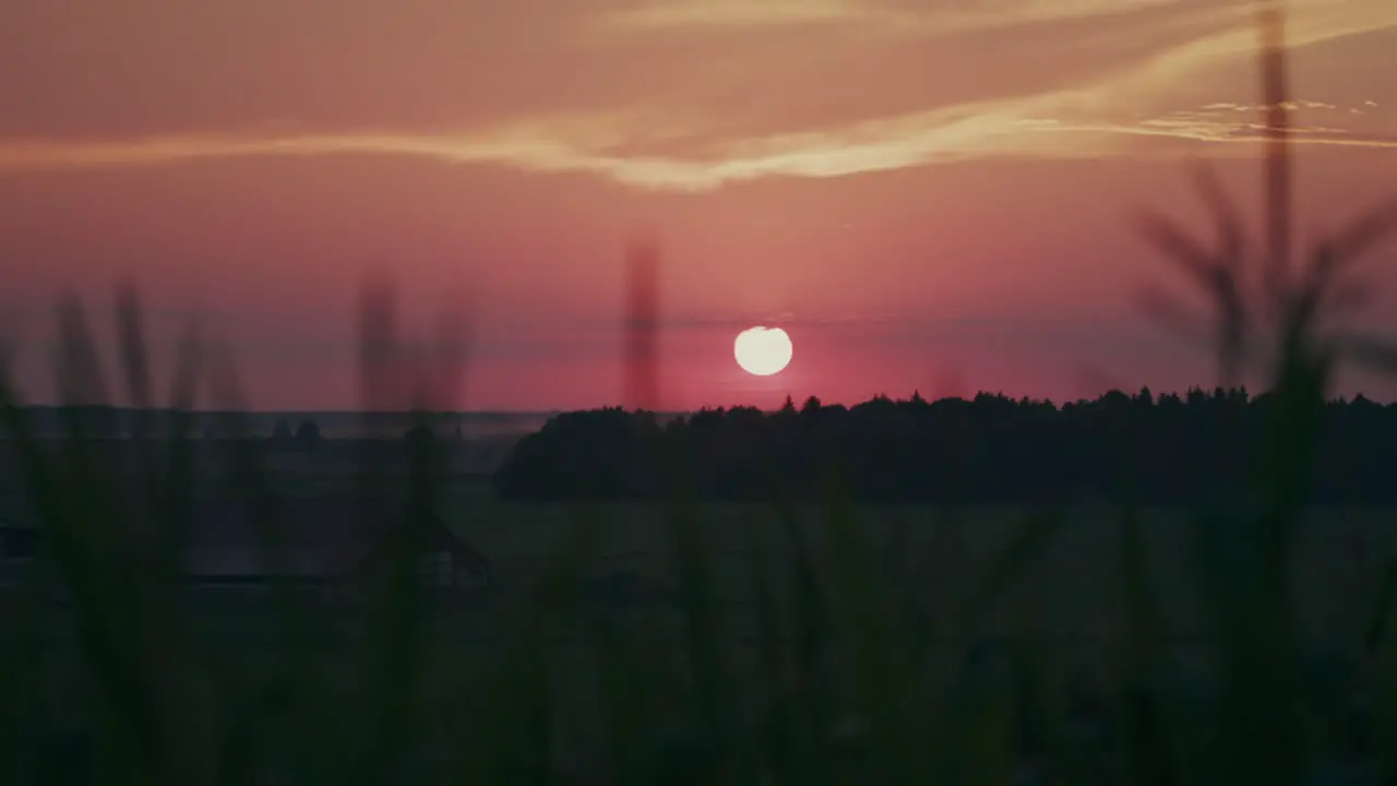 Sun dips below calm countryside horizon in beautiful