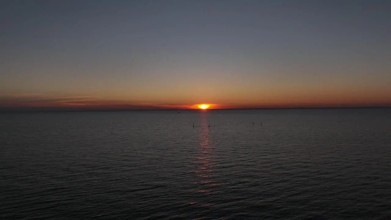 Aerial reverse of sunset as power boater cruises by