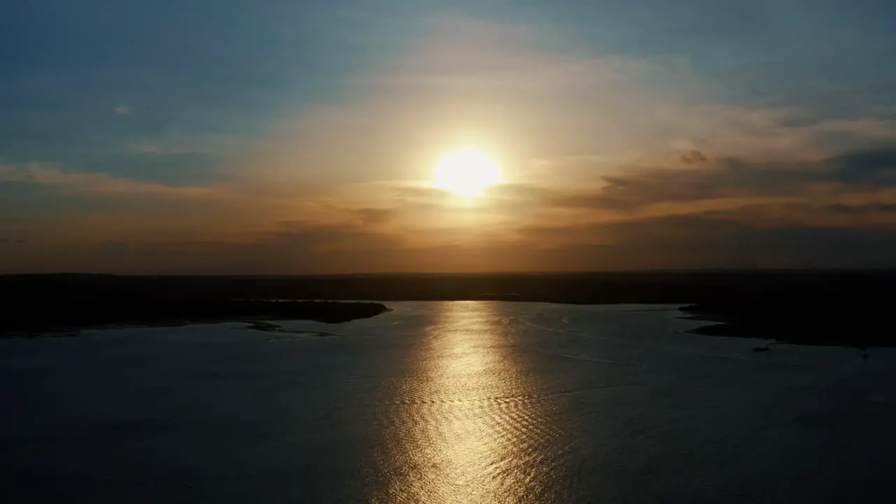 Stunning aerial drone static shot of a golden sunset reflecting onto the water of a large amazonian river in Joao Pessoa Brazil