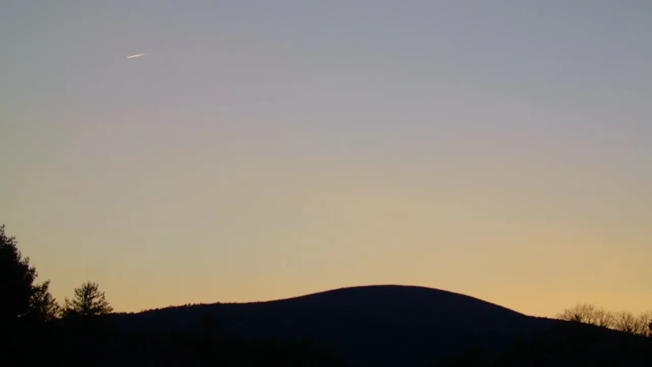 Plane Flying in Distance over Mountain at Sunset