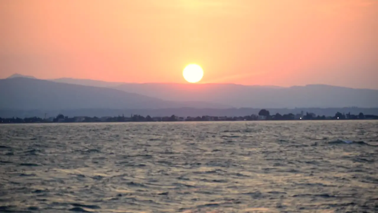 Ducks flying by in front of a beautiful dawn in Italy Garda Lake