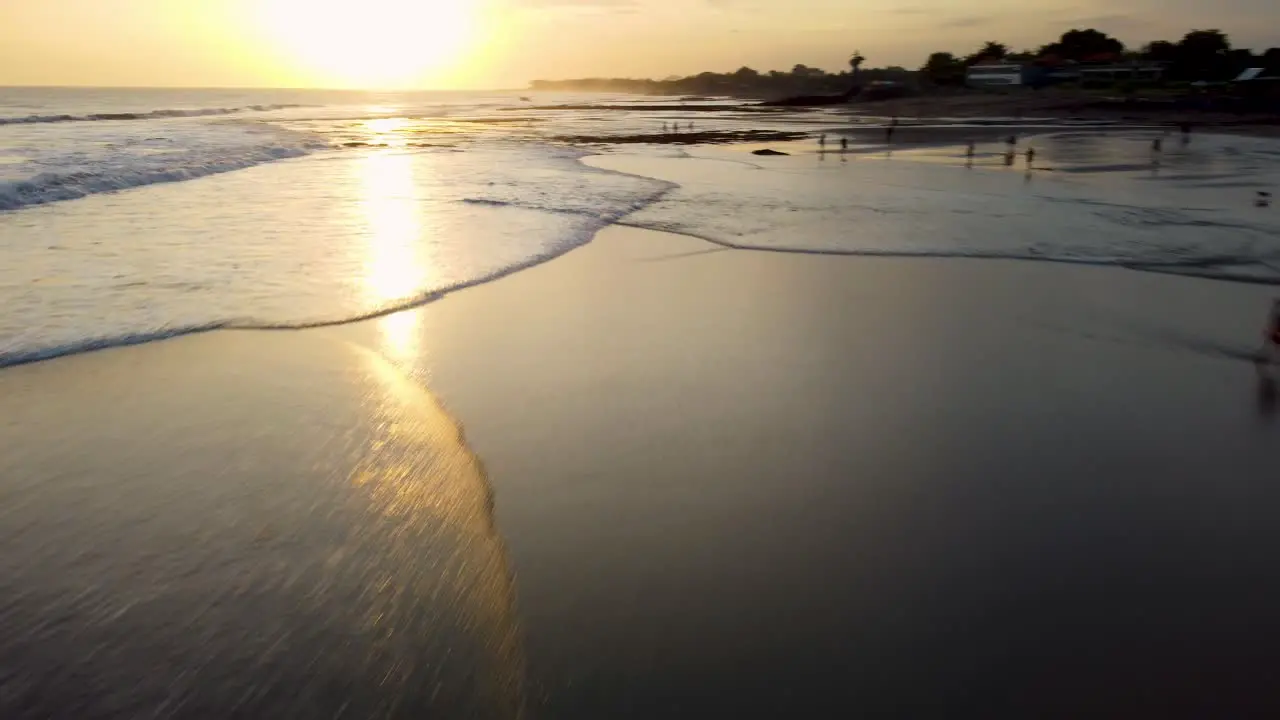 AERIAL Drone shot showing the waves and tourists on a bali beach