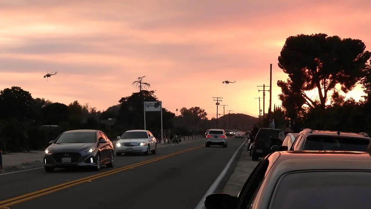 A fiery orange evening sunset with helicopters flying over traffic