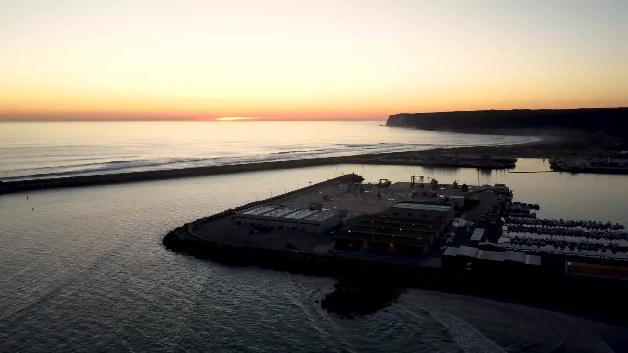 Establishing drone shot over a sea fishing port during sunset