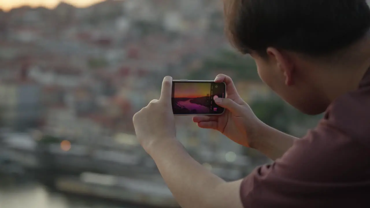 A tourist in the city of Porto taking a picture of the sunset in public