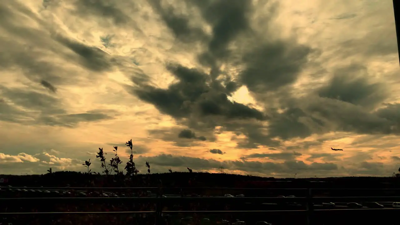 Plane approaching landing at sunset against the background of orange sun behind clouds