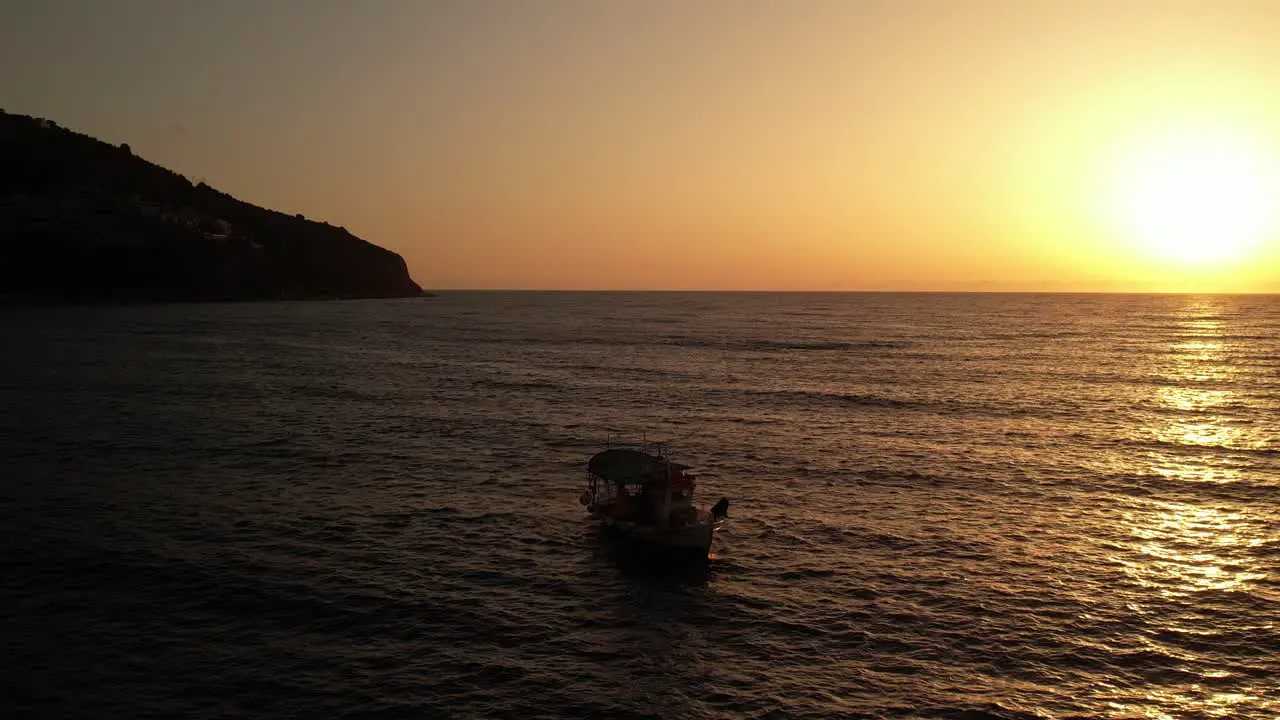 A small fishing boat throws nest while the sun sets in beautiful Greece while the sea is calm