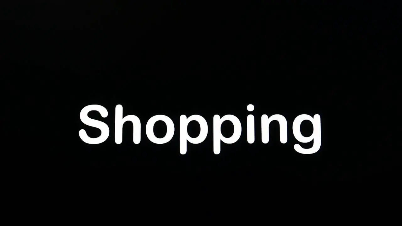 Typing on the screen with a flashing paragraph forming the word Shopping in white on a black background