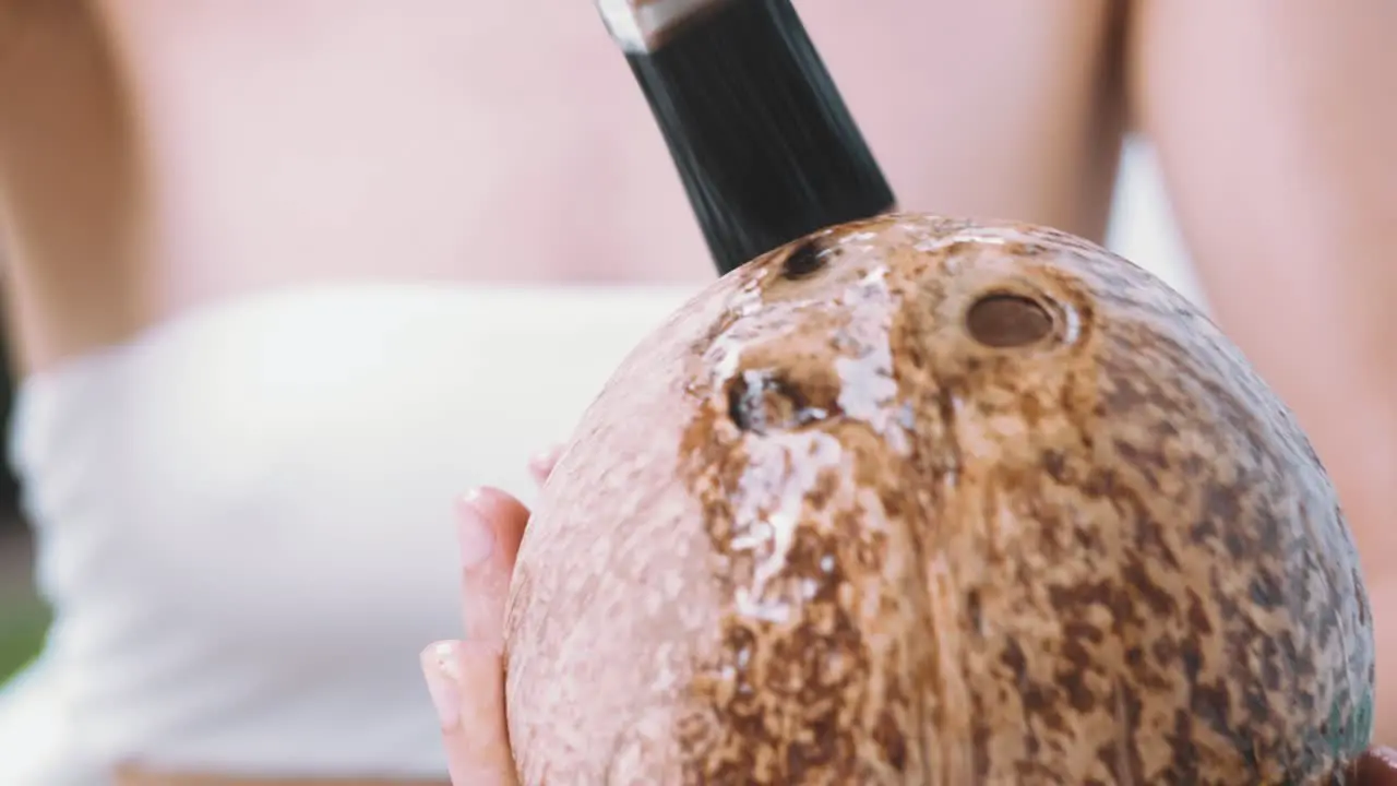 Close up of female hands covering a sanded coconut shell with oil