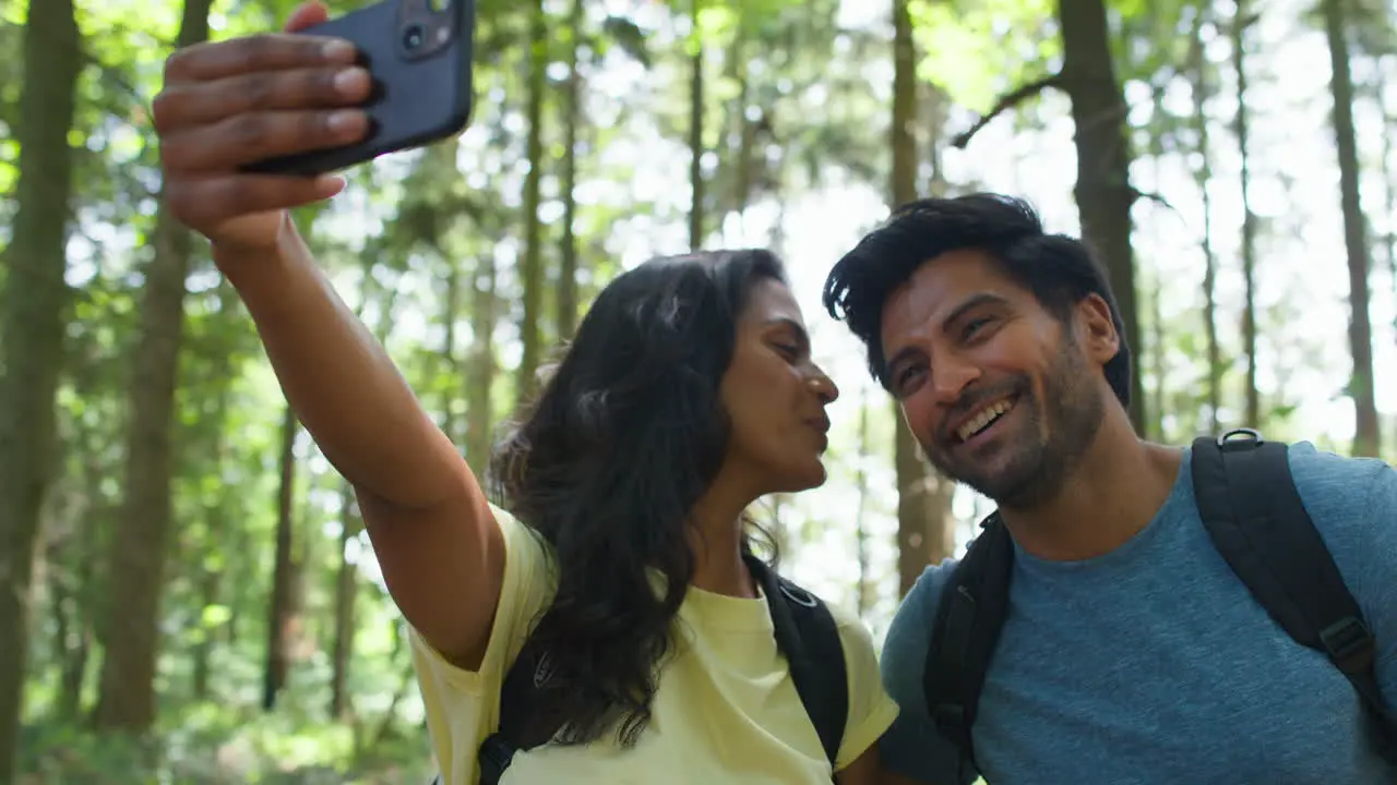 Couple Taking Selfie With Mobile Phone Hiking Or Walking Through Summer Woodland Countryside