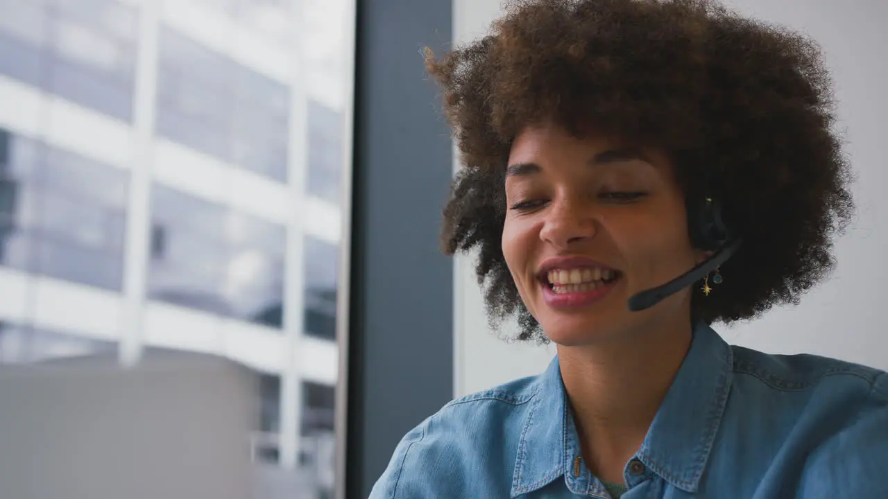 Young Businesswoman In Modern Office Working On Laptop Using Wireless Headset