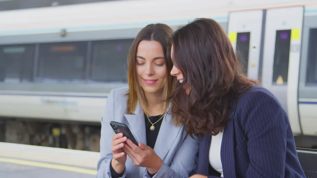 Businesswomen Commuting To Work Waiting For Train On Station Platform Taking Selfie On Mobile Phone