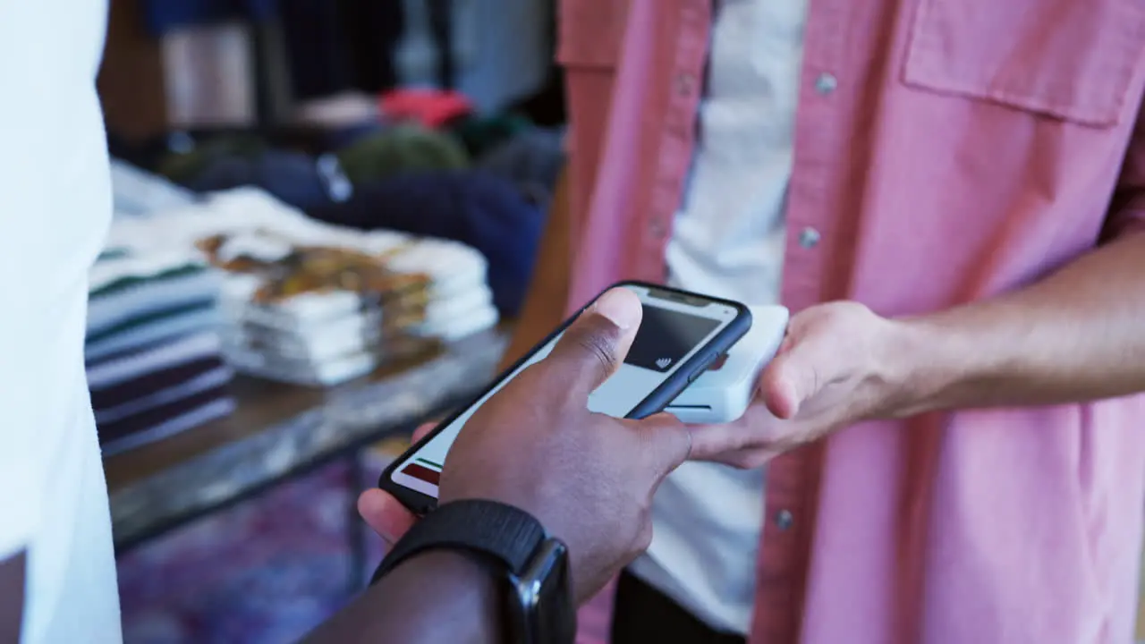 Woman In Clothing Store Making Contactless Payment With App On Mobile Phone