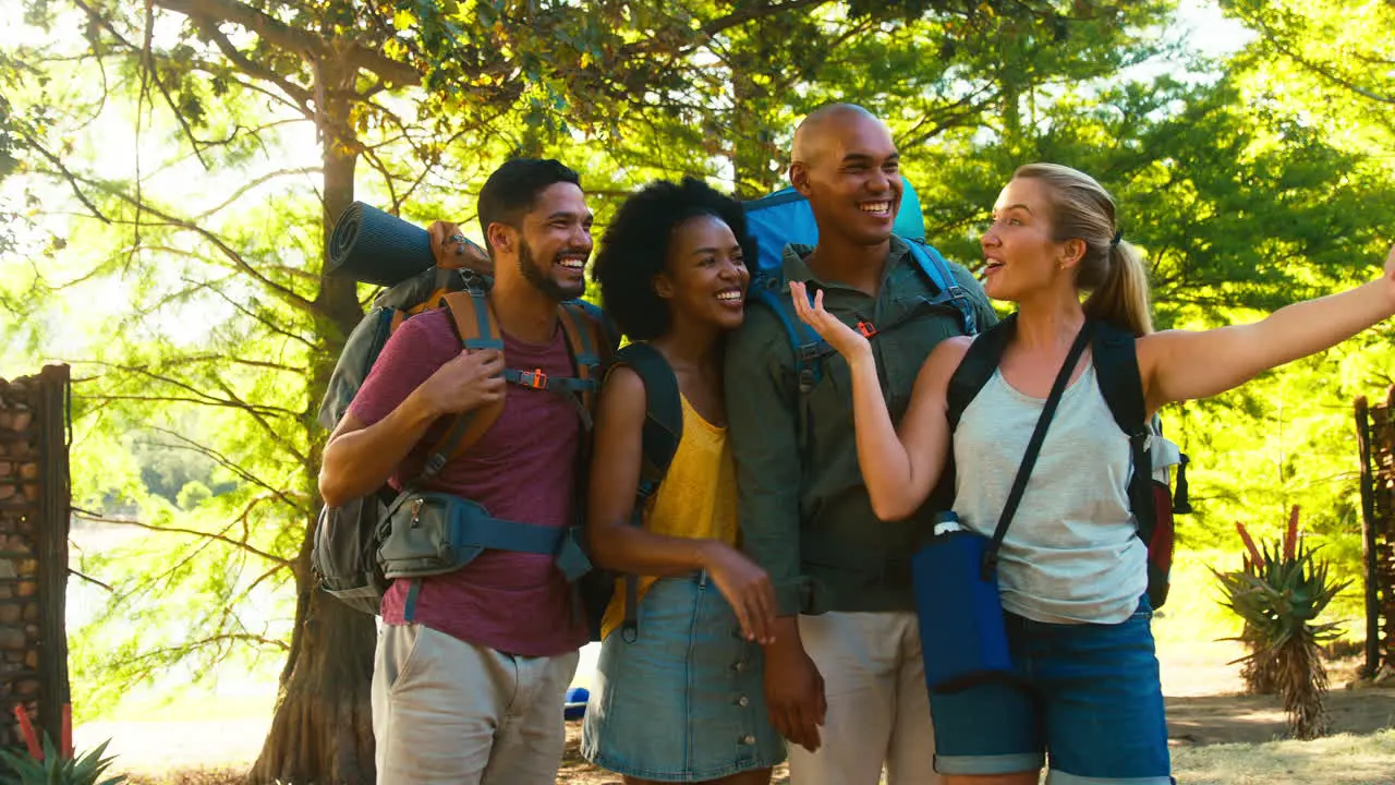 Group Of Friends With Backpacks Making Video Call On Mobile Phone Whilst Hiking In Countryside