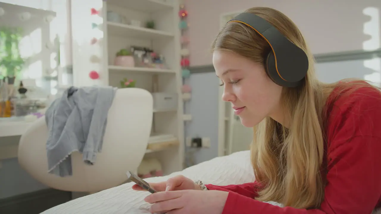 Teenage girl wearing wireless headphones streaming music or film from mobile phone -s hot in slow motion