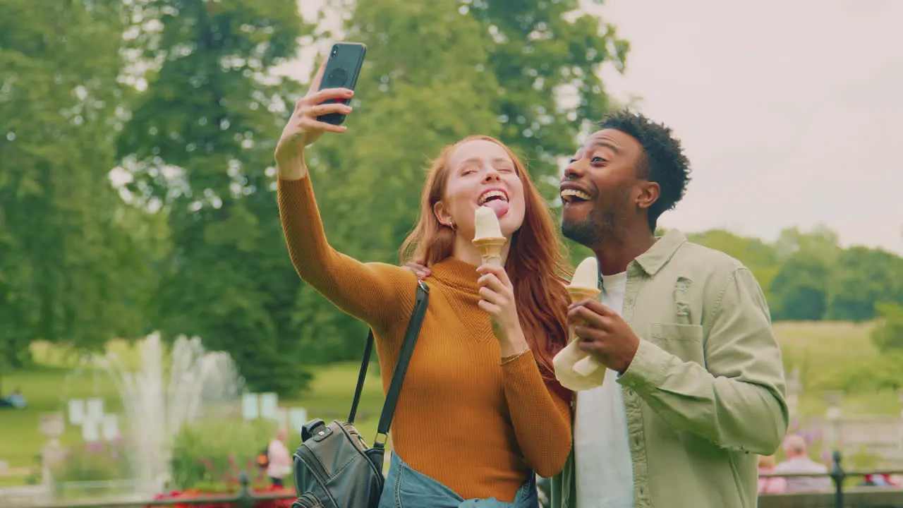 Young Couple Travelling Through City Together Eating Ice Creams In Park