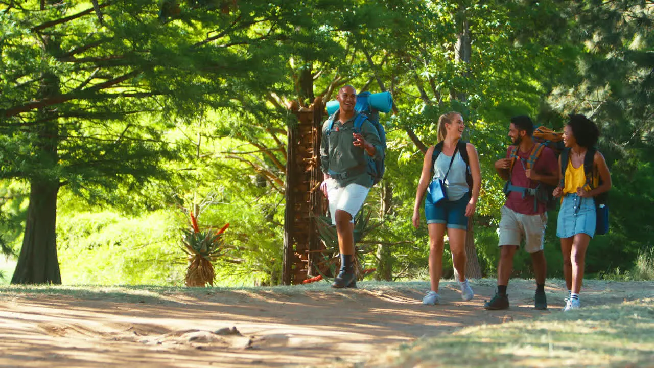 Group Of Friends With Backpacks Using GPS On Mobile Phone On Vacation Hiking In Countryside