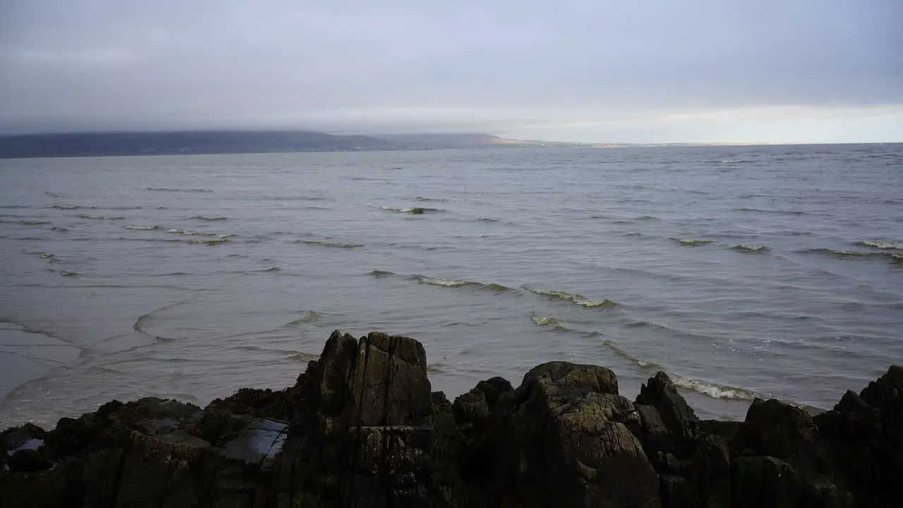 View of the sandy beach and the waves on the sea rocky coast and cloudy sky in Dundalk Ireland