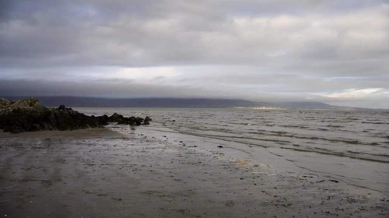 Mud and sand on the beach sea waves and rocky coast  cloudy sky in Dundalk Ireland