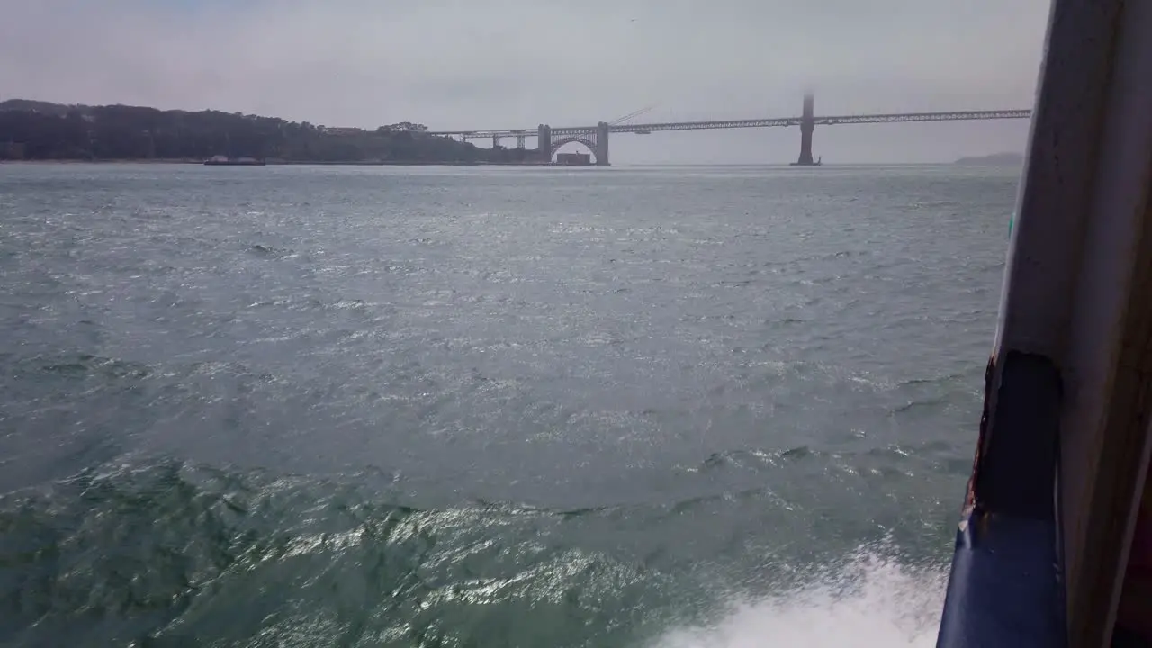 Gimbal shot of a seagull riding the wind currents along the side of a boat as it approaches the Golden Gate Bridge in San Francisco in the fog