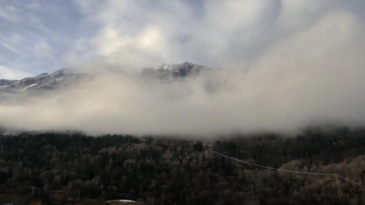 Time lapse of low cloud in a valley slowly clearing to reveal mountain tops in the background