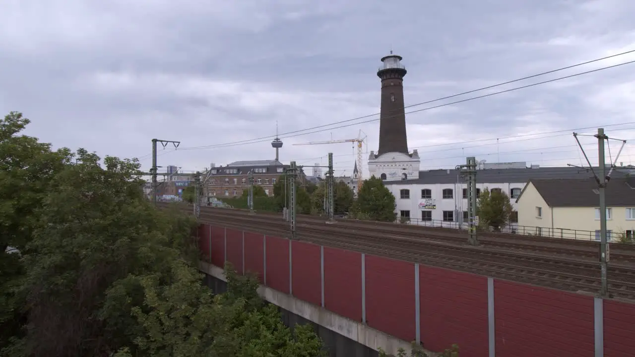 A commuter train on the way to Aachen in Cologne Ehrenfeld on a cloudy day in front of the panorama scenery of Cologne Ehrenfeld with the TV tower in the background