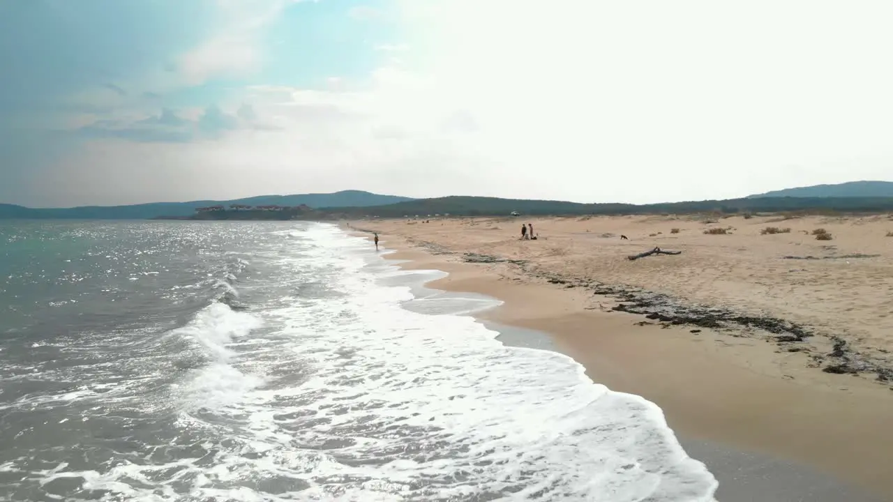 Aerial footage drone shoot parallel to sea shore flying above waves and sand Sozopol Bulgaria