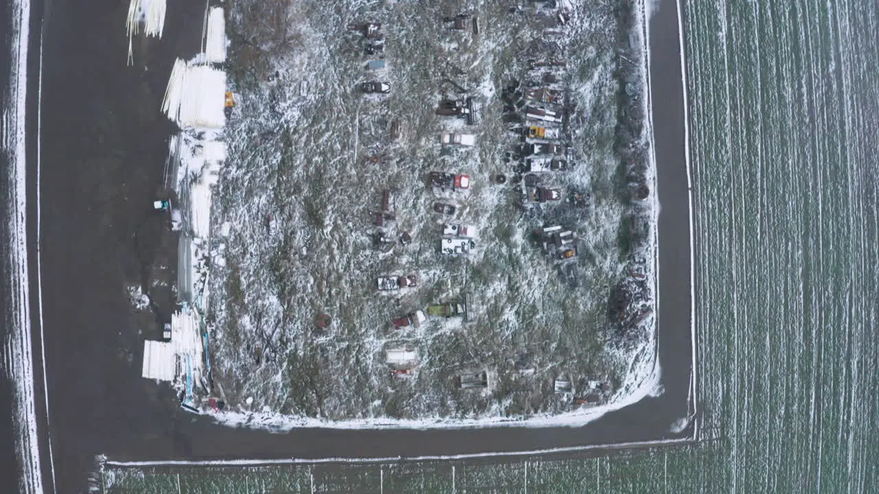 Flying over a field of dilapidated cars on a wintery snowy farm in Tehachapi CA