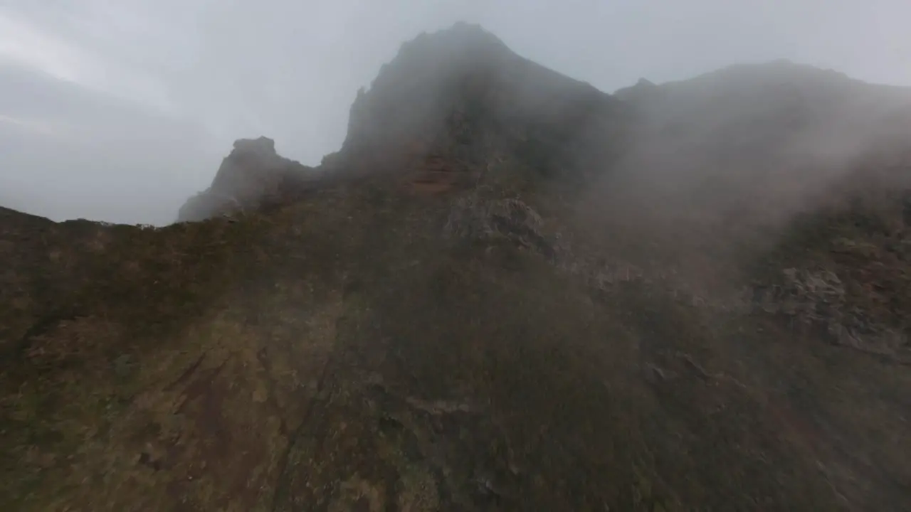 FPV drone flying close to the rocks through fog and clouds in the mountains at Madeira