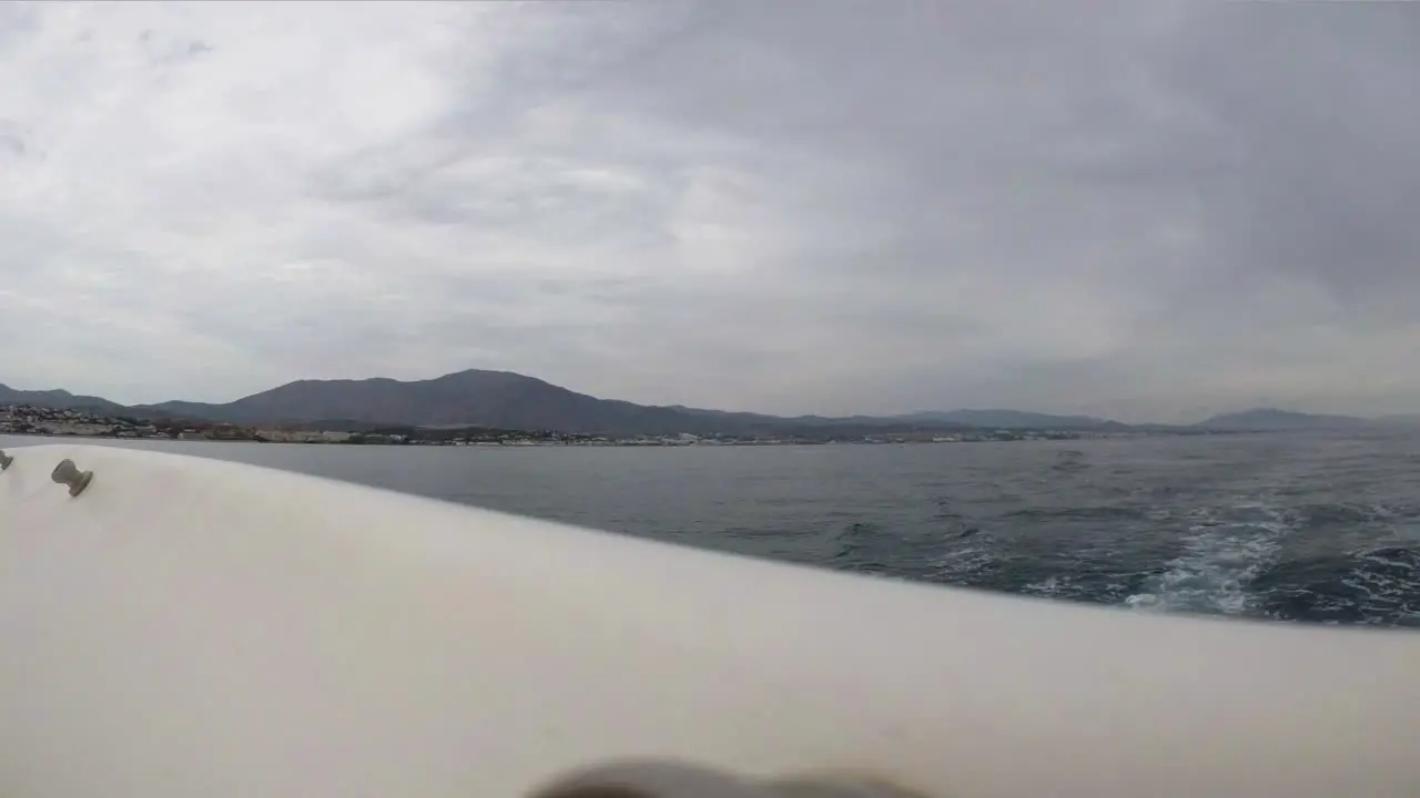 View of coastline mountains from sailing boat stern