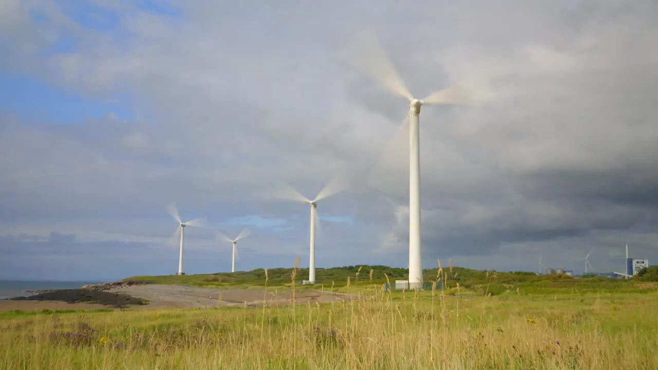 Wind farm spinning and storm clouds gathering with sunlit pools moving across landscape