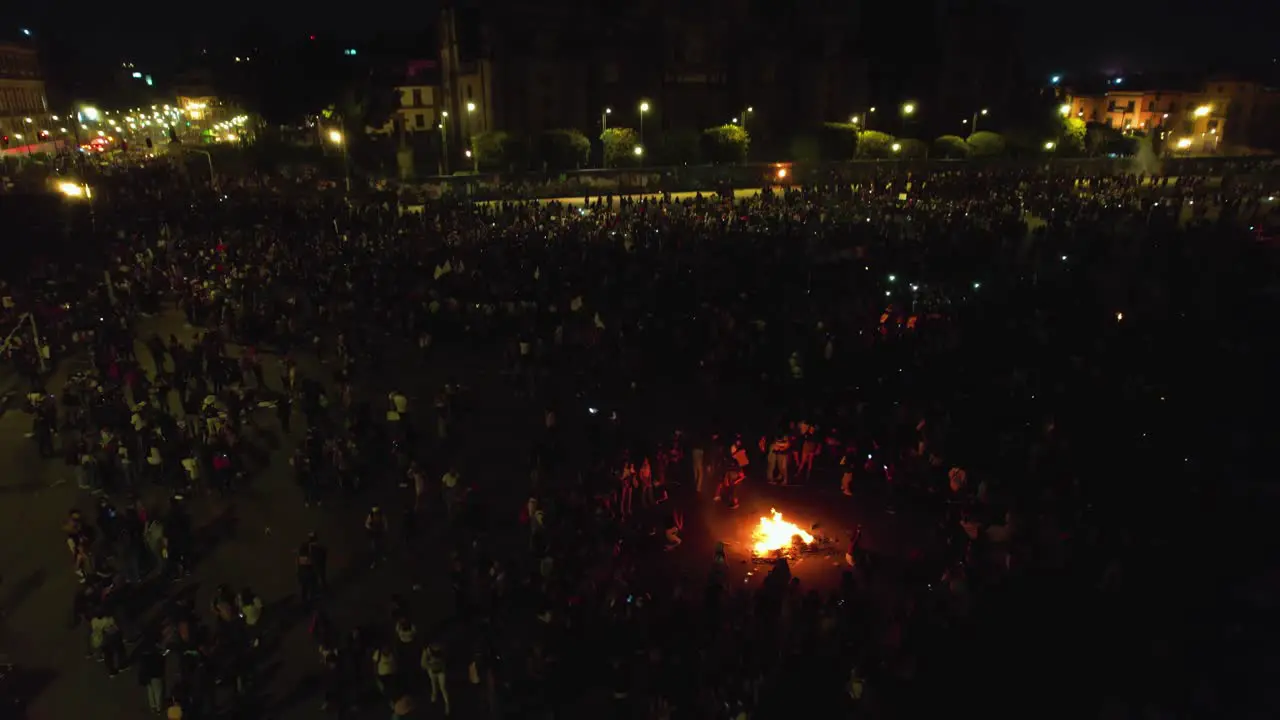 Aerial view over protesters having a bonfire on a large city square tilt drone shot