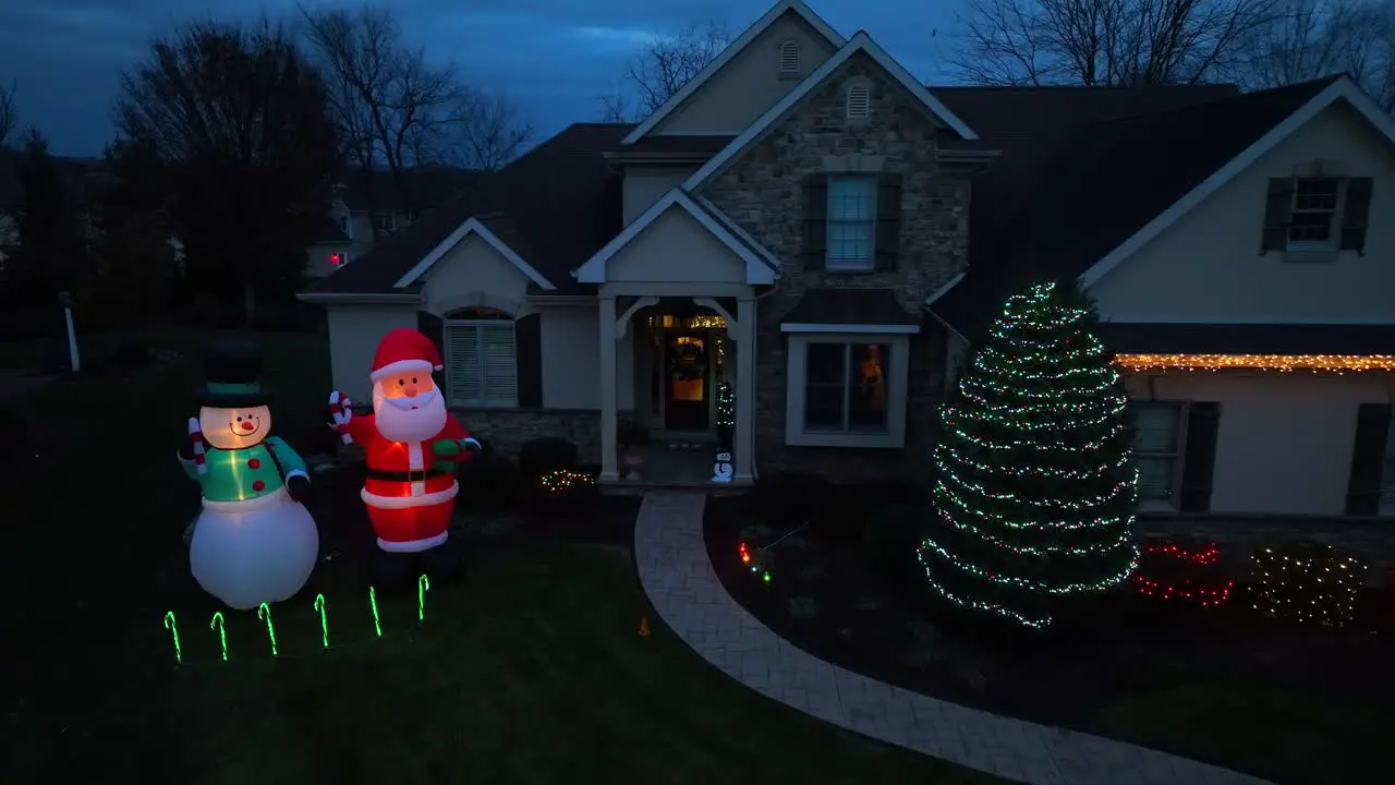 Inflatable Santa and Frosty the Snowman with Christmas light decorations at two story American home during holiday season