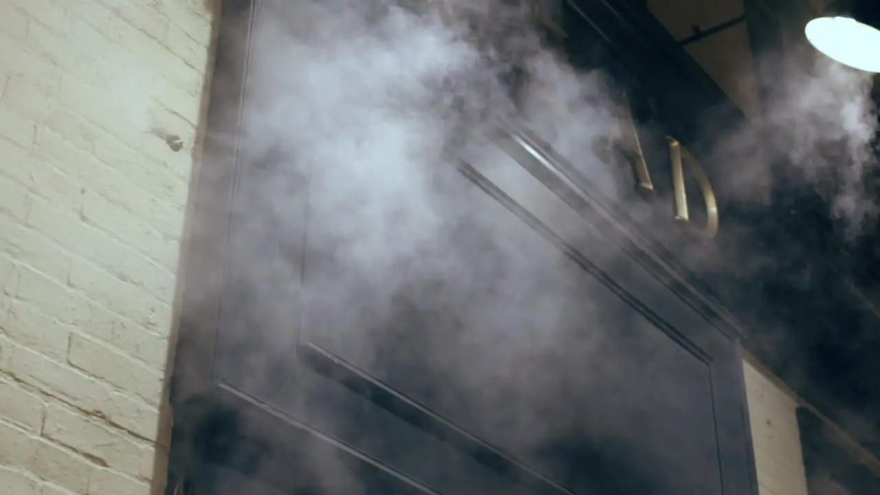 Steam creepily rising next to an exterior brick wall and doorway at night