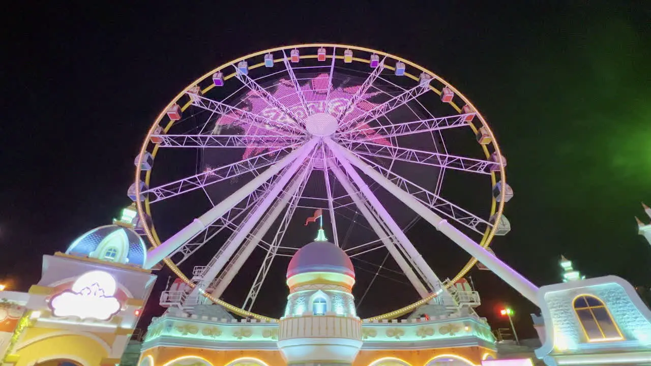 Ferris wheel with video projection at the entrance of the adventure park at Global village theme park seen at night