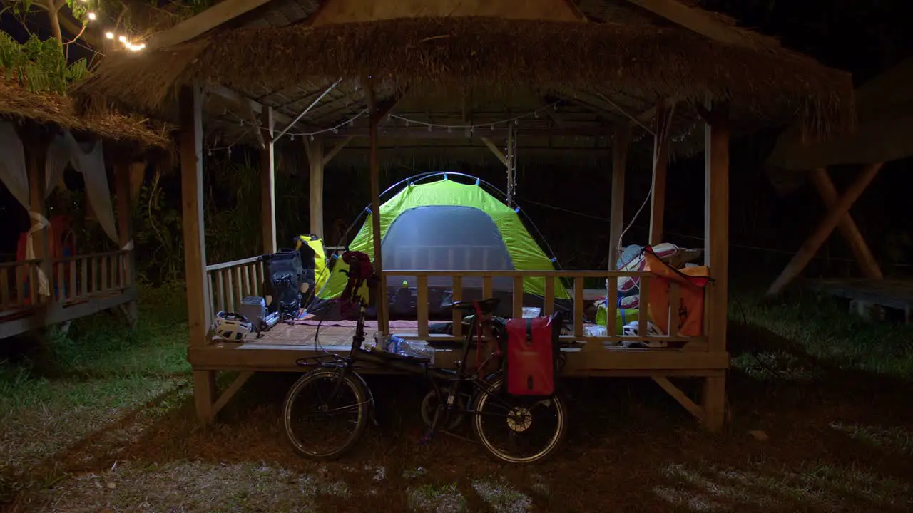 Illuminated tent mounted on top of an wooden hut structure at night