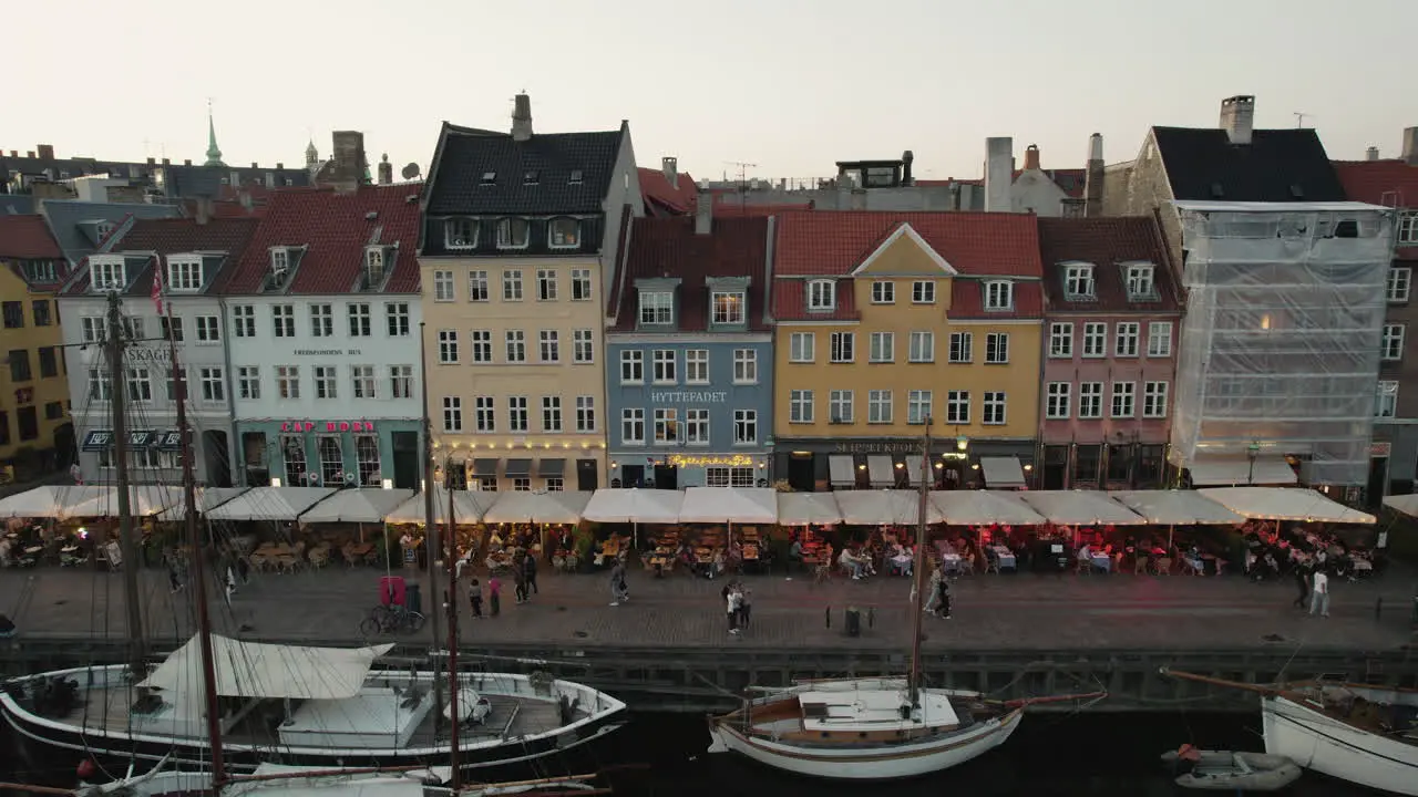 A picturesque sunset over Nyhavn Copenhagen setting a cozy mood with lively crowds and boats sailing along the canal