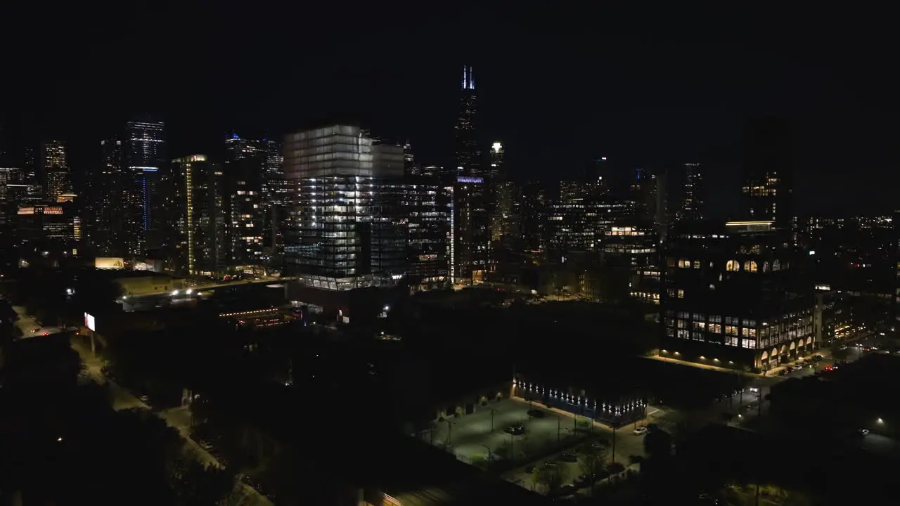 Drone shot over the Fulton River district toward night lit skyscrapers of Chicago USA