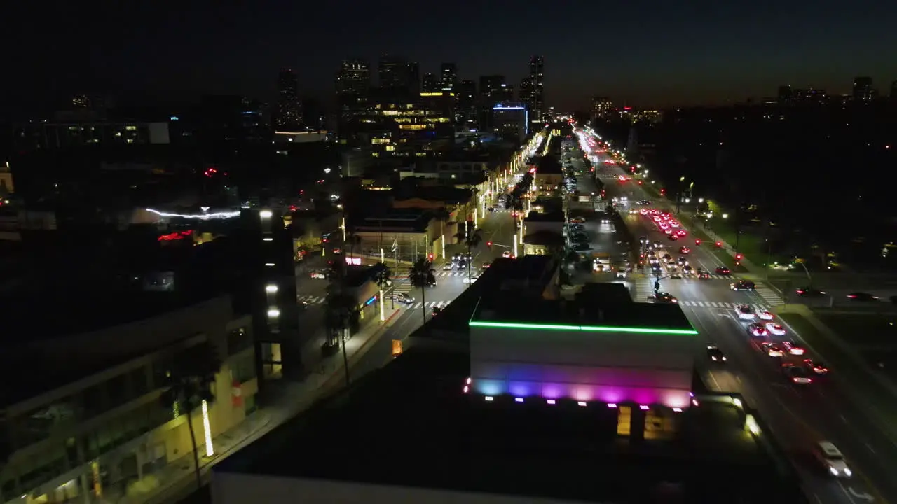 Drone shot over the colorful night lit cityscape of Beverly Hills Los Angeles