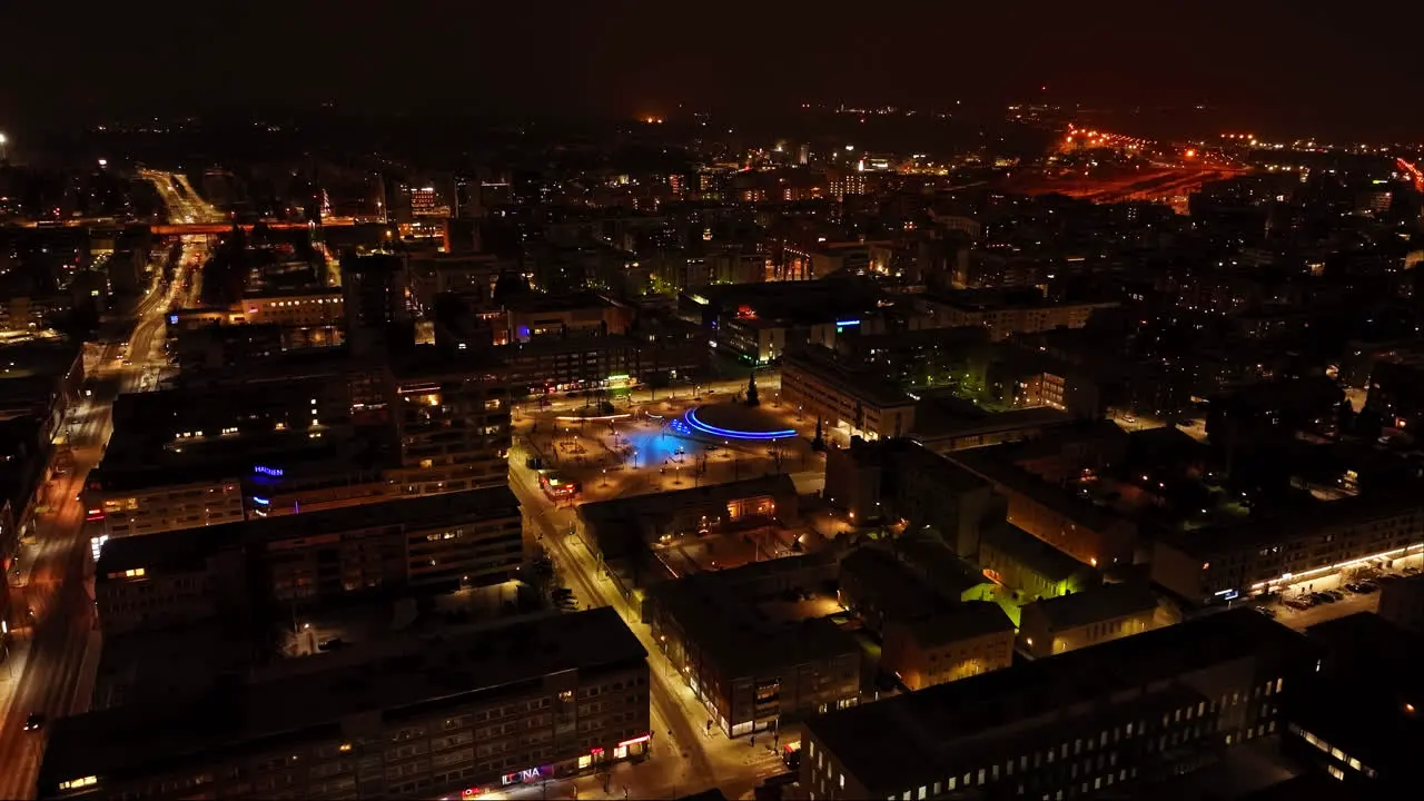 Aerial rising shot of a illuminated square in downtown Oulu winter evening in Finland