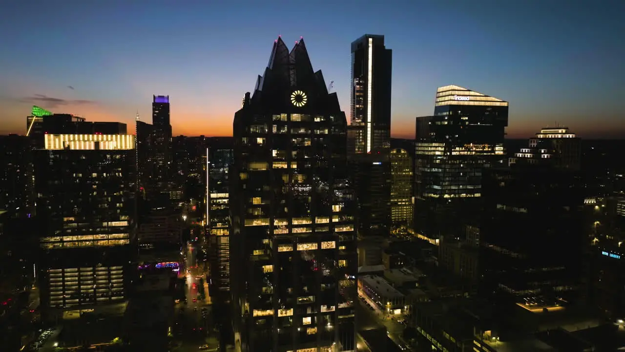 Aerial view rising around the Illuminated Frost bank tower dusk in Austin USA