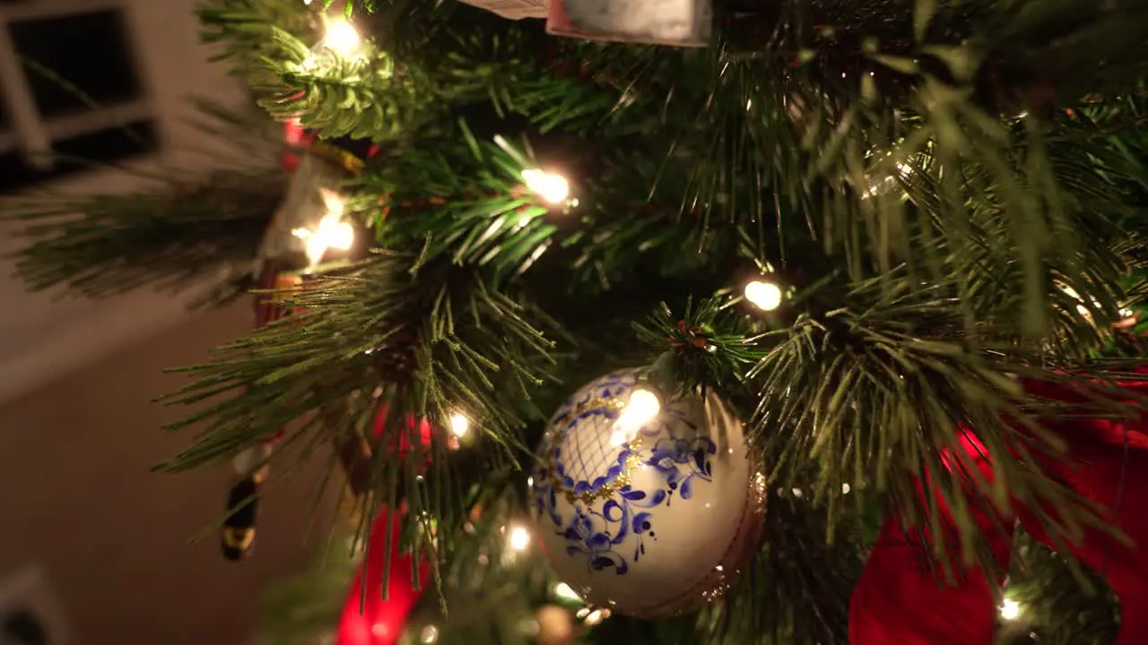 Dolly forward to focus in on a Christmas ornament on a tree