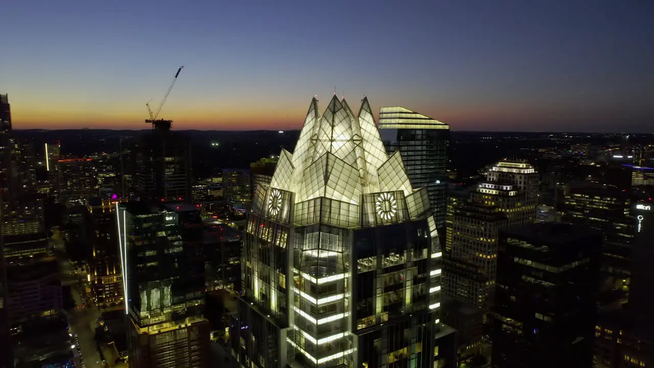 Aerial view around the Illuminated Frost bank tower in Austin USA orbit drone shot